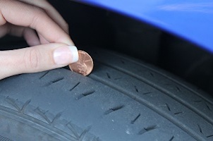 woman measuring tire tread depth with penny