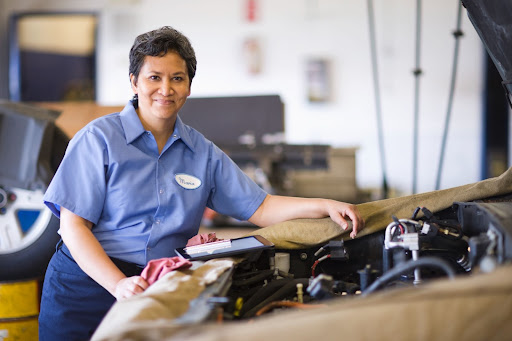 auto mechanic smiling at the camera while working on car repairs