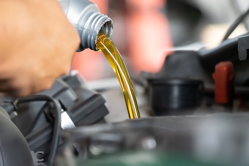 mechanic pouring oil into car engine during an oil change service
